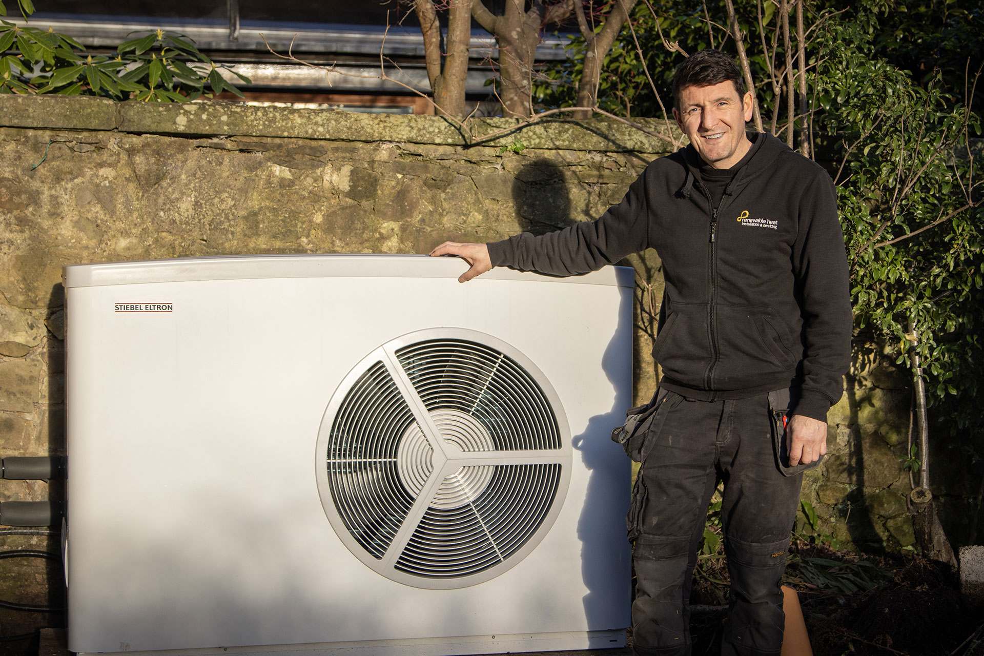 Renewable Heat engineer beside an installed air source heat pump